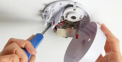 Certified technician wiring smoke detector during installation in Escondido, CA